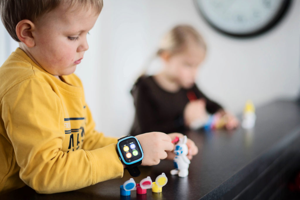 Tylsyys kannustaa luovuuteen. Lapsi maalaa keskittyneesti. Xplora 5 puhelin on lapsen ranteessa.