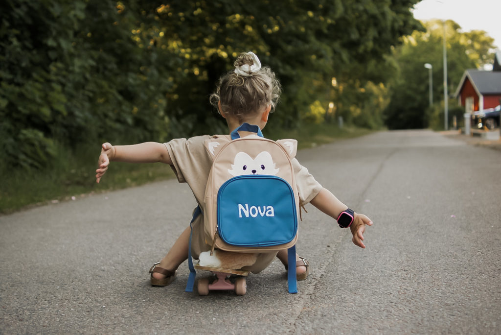 Lapsi istuu skeittilaudalla reppu selässä. image00024