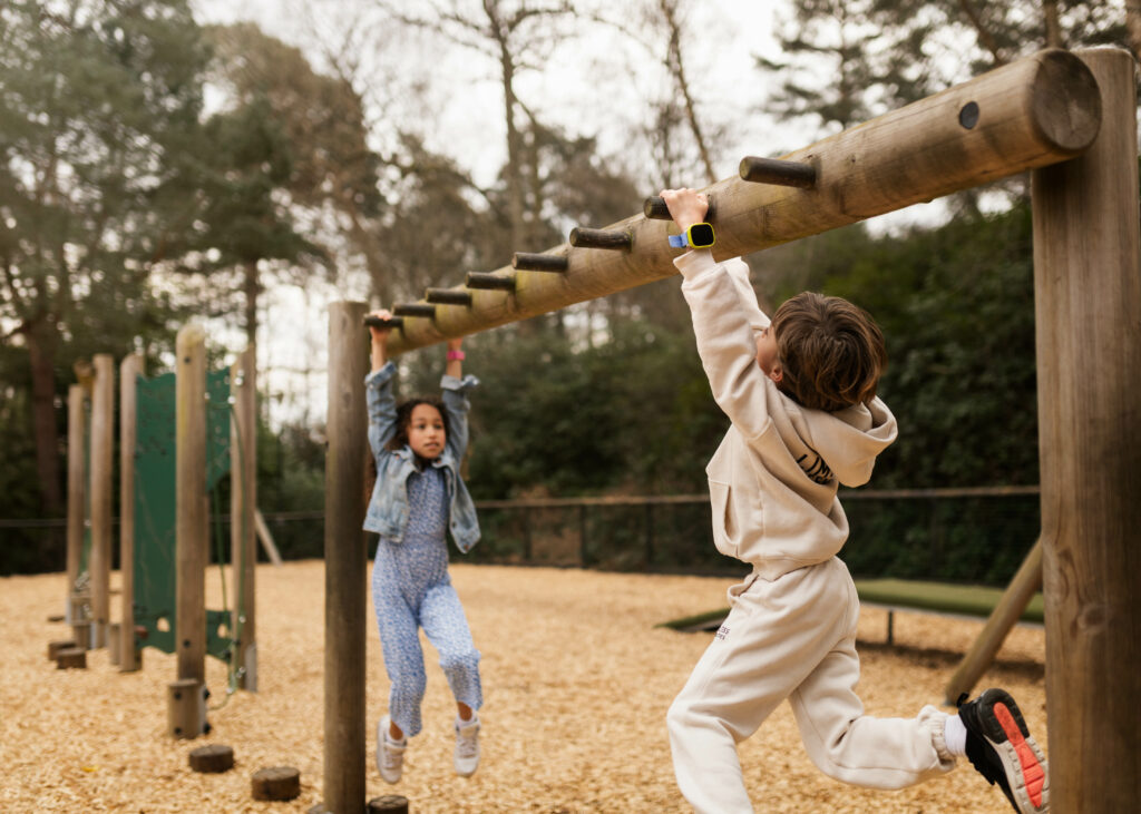 Lapset roikkuvat kiipeilytelineessä Xplorat ranteessa. Lapset roikkuvat kiipeilytelineessä kellopuhelimet ranteessa.