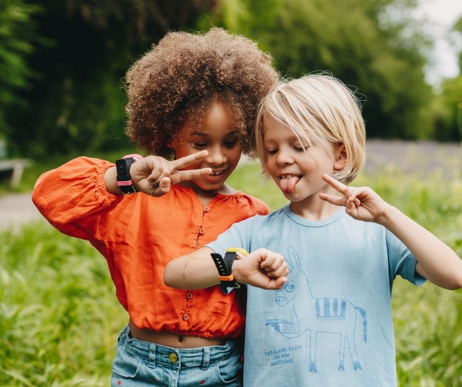 Lapset ottavat selfien kellopuhelimella. SOS-toiminto mahdollistaa yhteyden huoltajaan napin painalluksella.